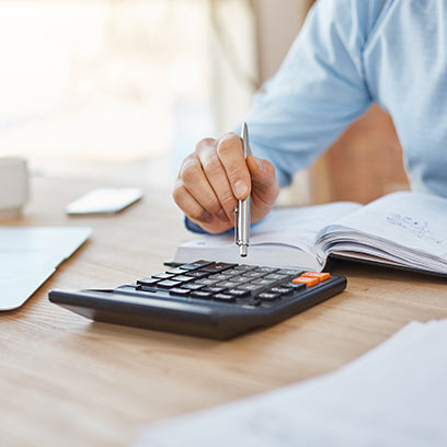 A man focused on a calculator at his desk, engaged in his accounting course studies.